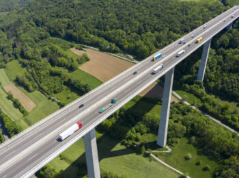 Luftaufnahme einer Brücke. Darauf sind LKW und Autos.